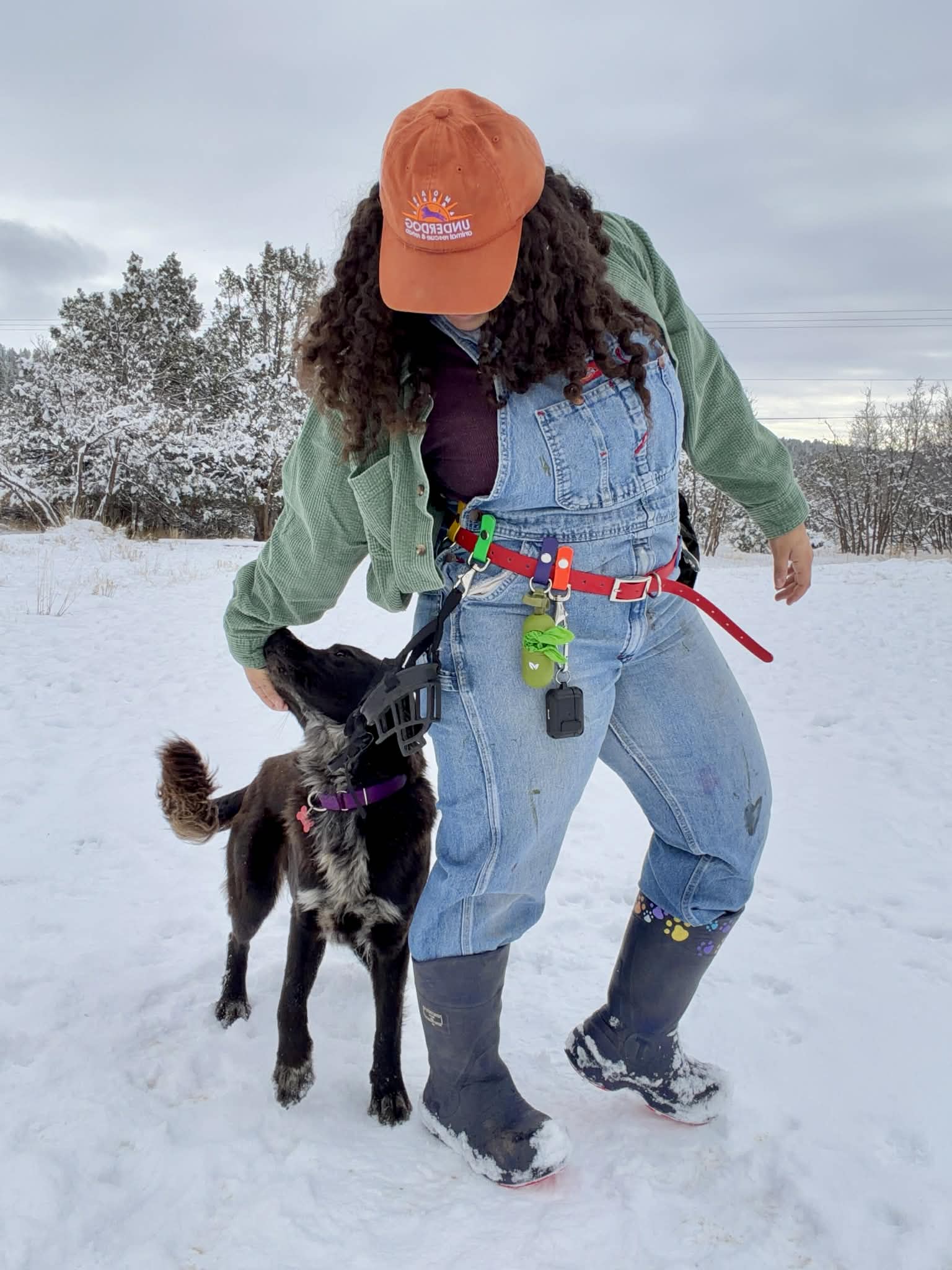 woman wearng biothane training belt with poop bag holder attached and brown dog next to her